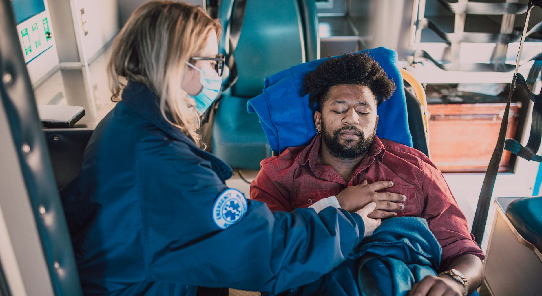 A paramedic attends to an injured man in an ambulance, ensuring his safety and comfort.