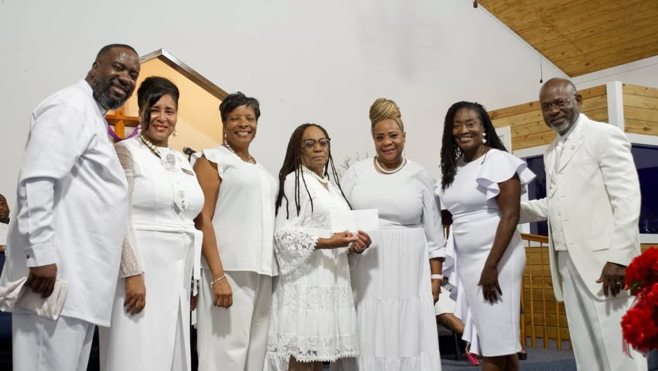 Representatives from SUSLA, BMELA, and Peaceful Rest dress in all white Sunday best, smiling at the camera.