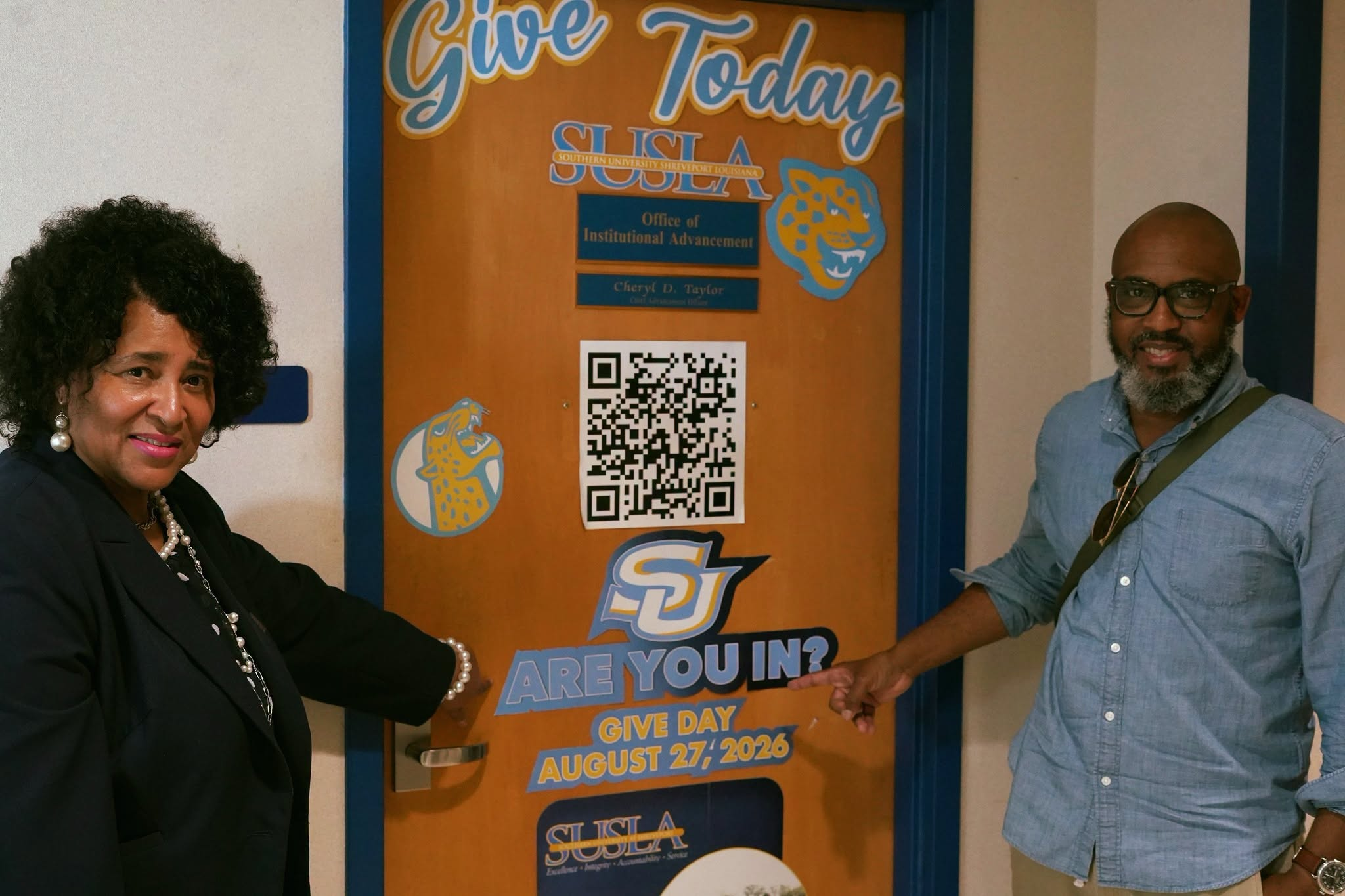SUSLA employees present an office door decorated in ARE YOU IN? promotional materials.