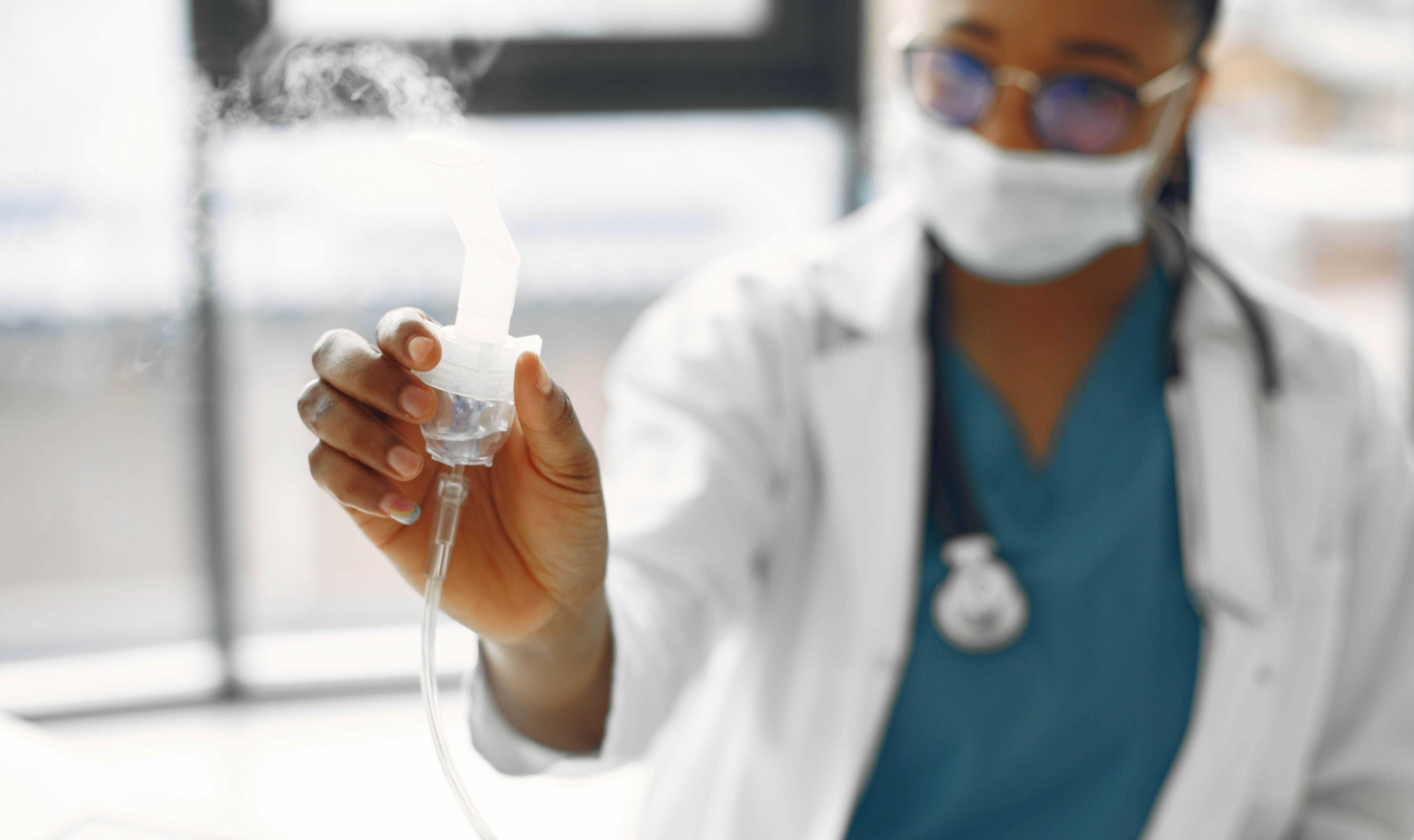 Close-up of a healthcare worker holding a nebulizer, showing focus on medical equipment.